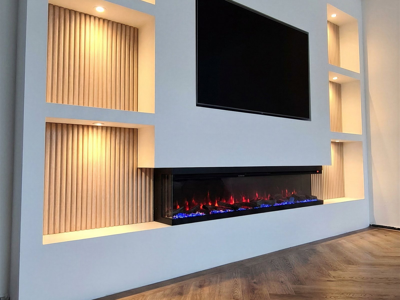 3D sfeerhaard driezijdig ingebouwd in een tv wand met verlichte nissen van houten panelen, vlam zichtbaar van voren en opzij