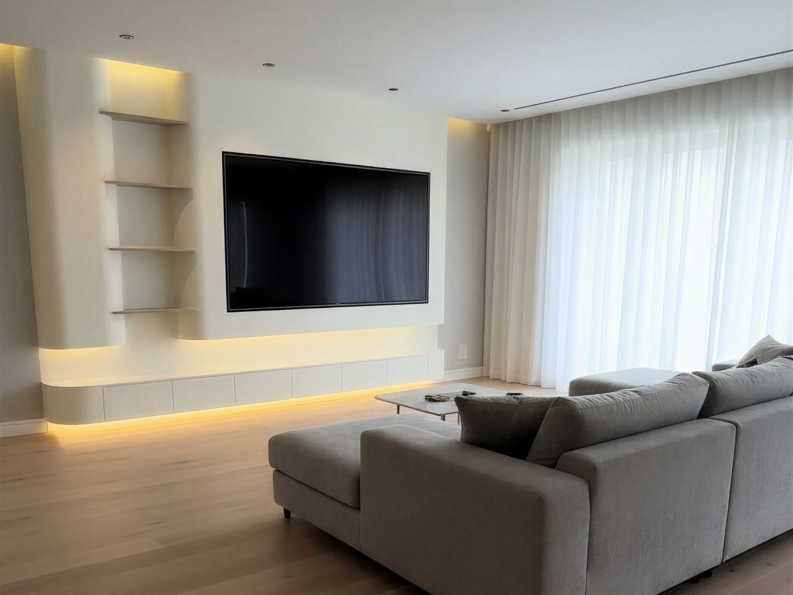 Cinewall met kastruimte: open planken naast de tv en een lang zwevend kastmeubel met warme ledverlichting