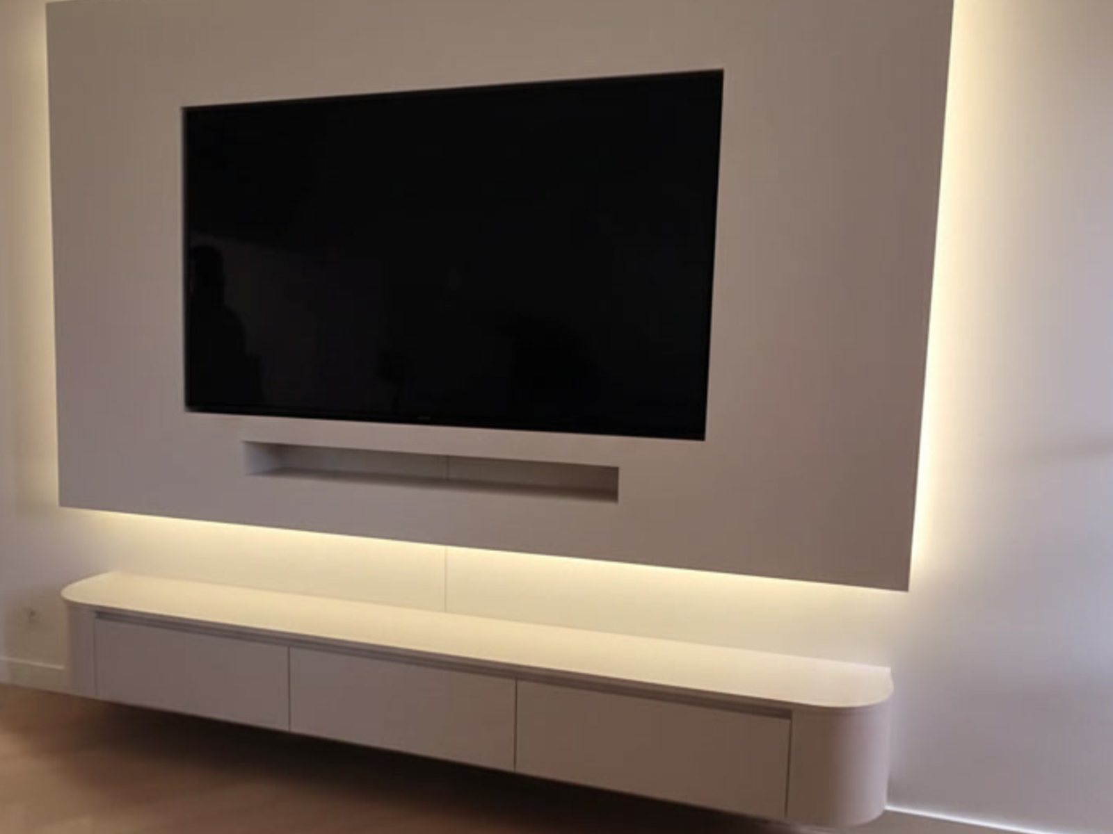 Maten van een cinewall met kastruimte: greeploze lades in een afgeronde zwevende kast met ledverlichting