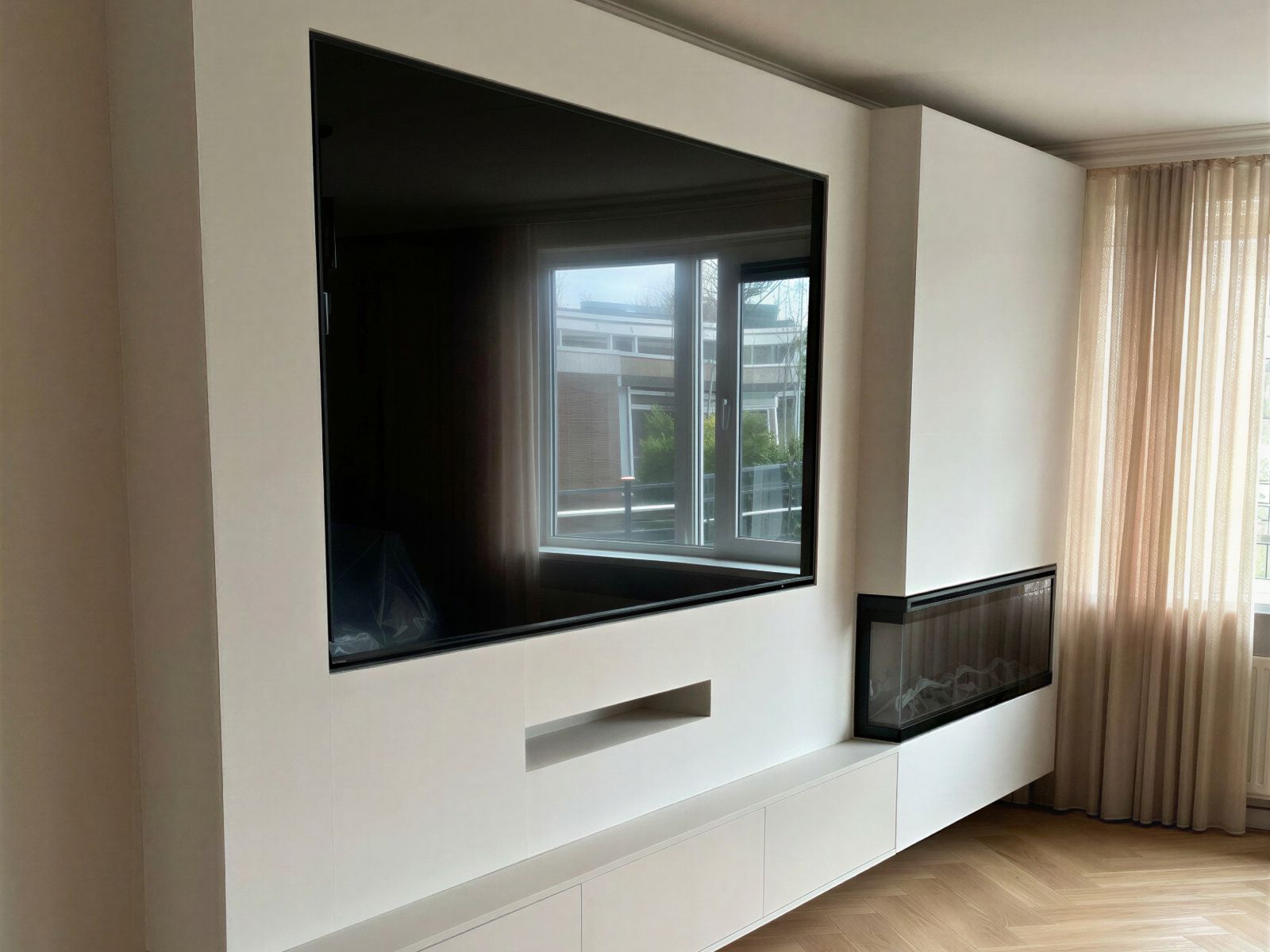 Prijsbepalende factoren van een cinewall: afmeting van de wand, gladde beige afwerking, een zwevende kast, soundbar-nis en een ingebouwde elektrische haard