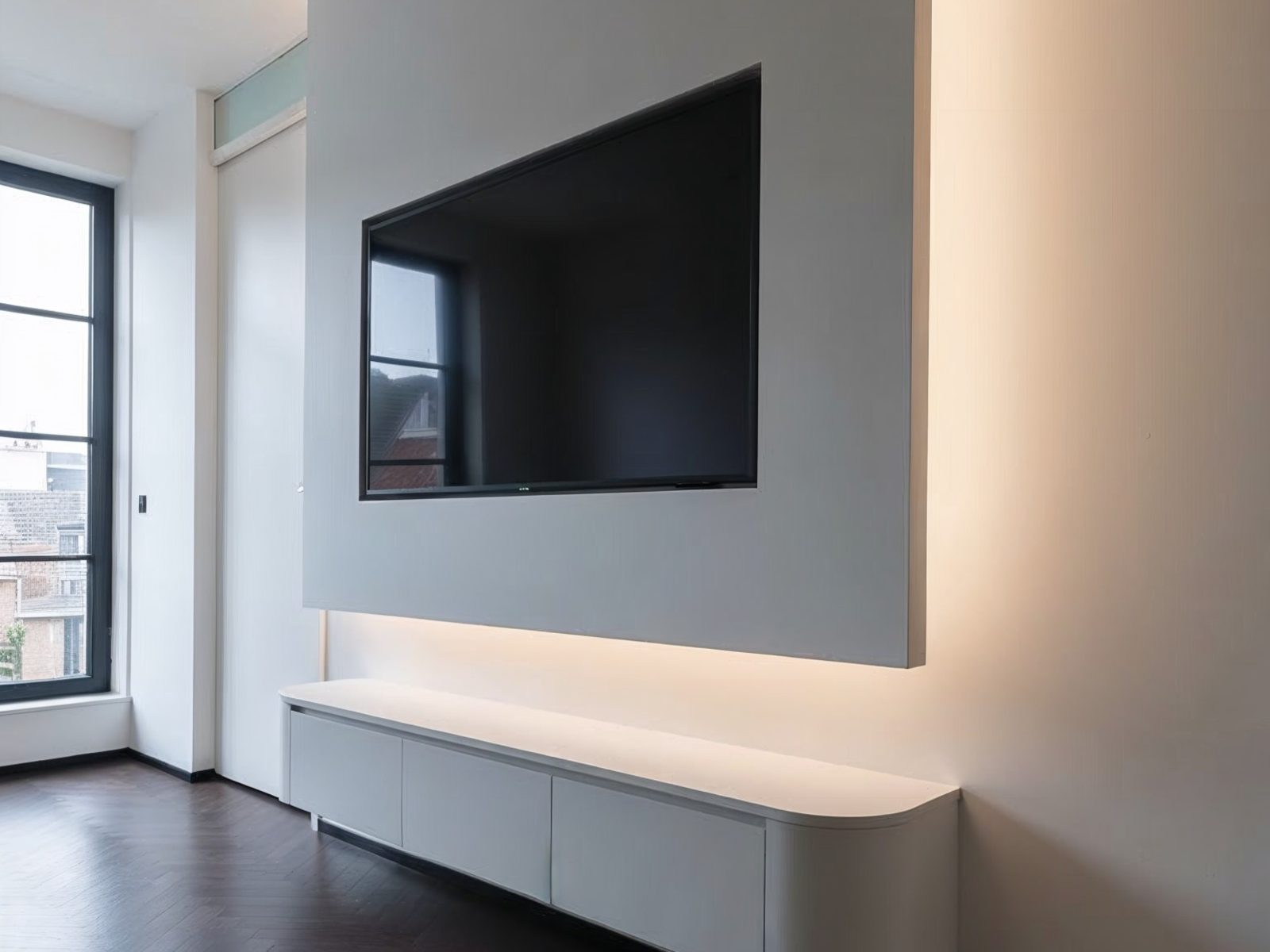 Zwevende cinewall met een kastmeubel dat los van de vloer hangt en indirecte ledverlichting die een warme gloed langs de wand geeft