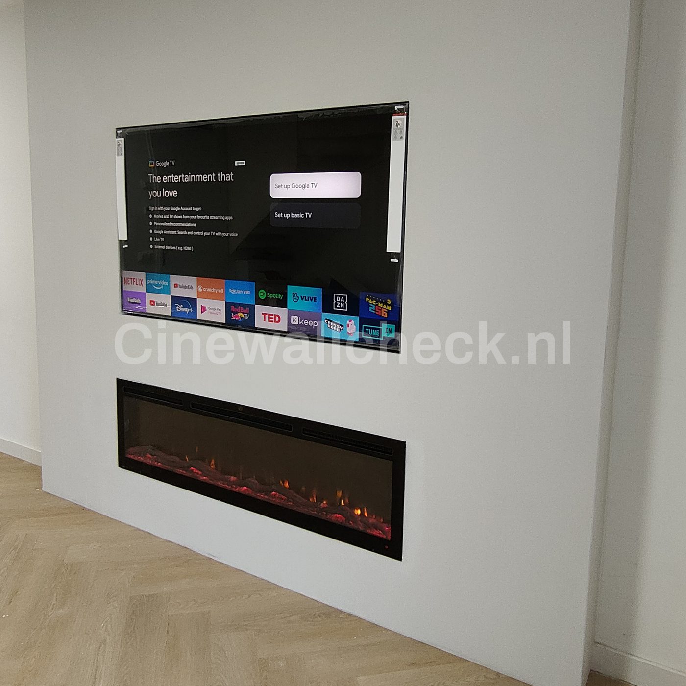 Tv wand met brede elektrische haard boven een visgraatvloer