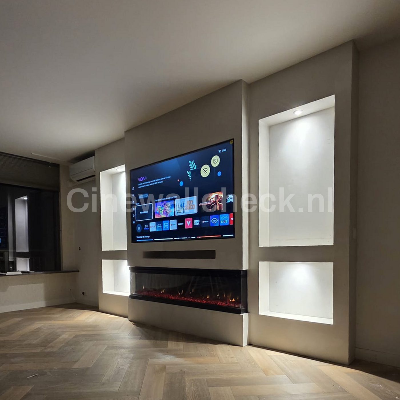 Cinewall in de hoek van de kamer met verlichte nissen en visgraatparket
