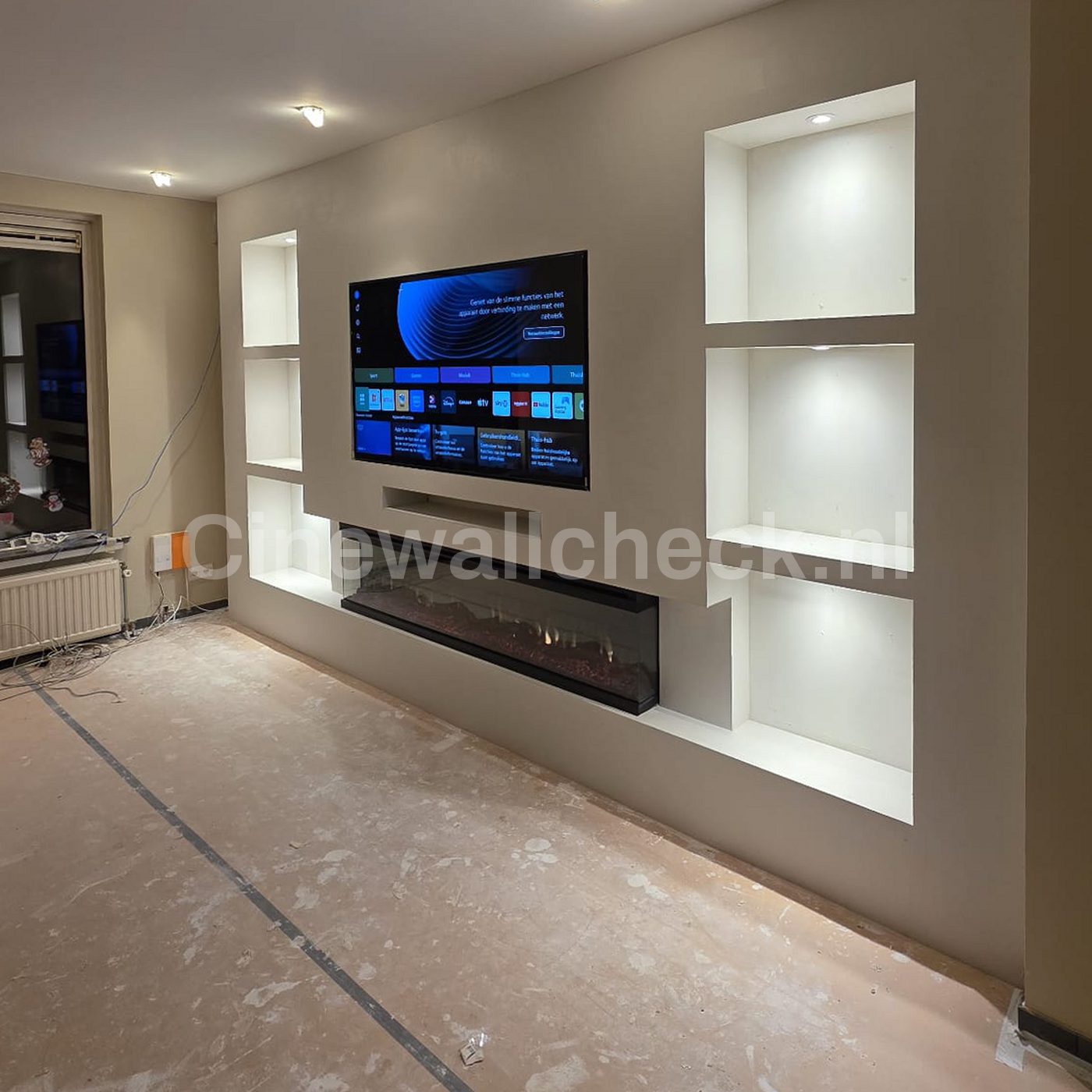 Cinewall in aanbouw met verlichte nissen en een brede haard