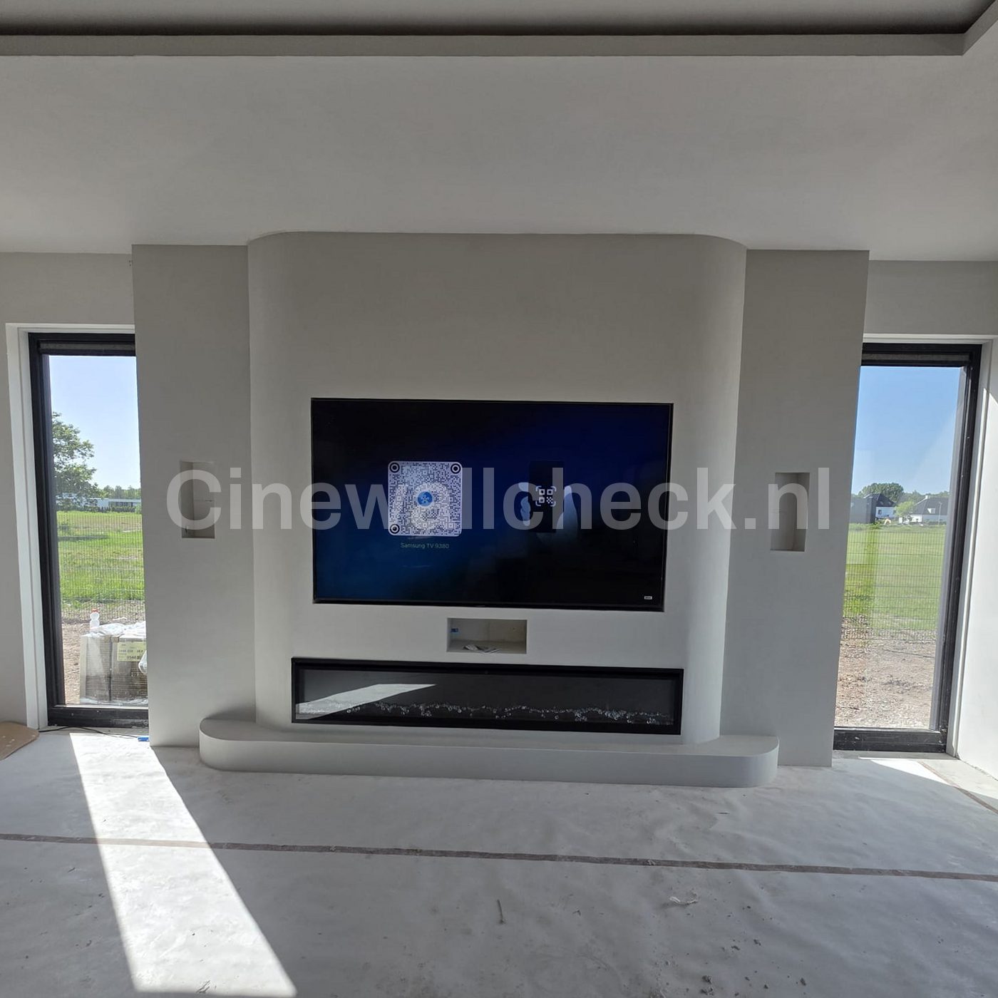 Cinewall met de tv tussen twee ramen en een haard eronder